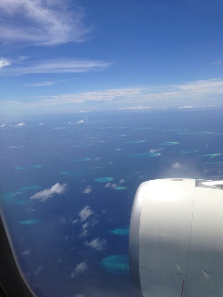Blick aus dem Flugzeugfenster, Meer, blau, türkis, Malediven, Malediven von oben, Foto aus dem Beitrag 10 hilfreiche Tipps gegen Jetlag: So überwindest du den Zeitzonenkater
