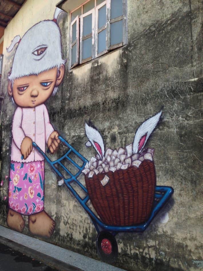 Streetart in Puhket Town, Thailand, Niedliche Figur, Schubkarre, Hasenohren an Hauswand 