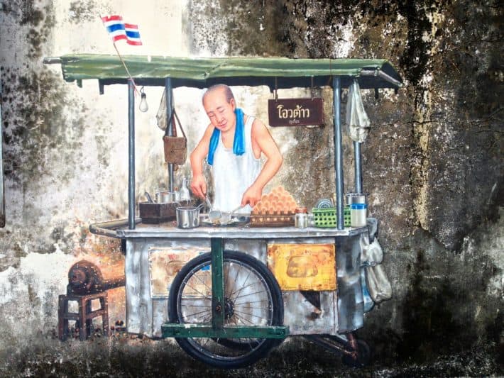 Streetart in Phuket Old Town, Thailand, Mann an Garküche bereitet Essen zu 