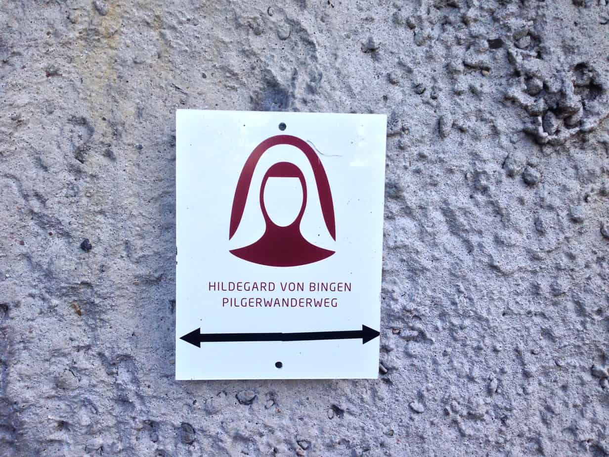 Wegweiser Hildegard von Bingen Pilgerwanderweg, weißer HIntergrund, bordeauxroter Nonnenkopf
