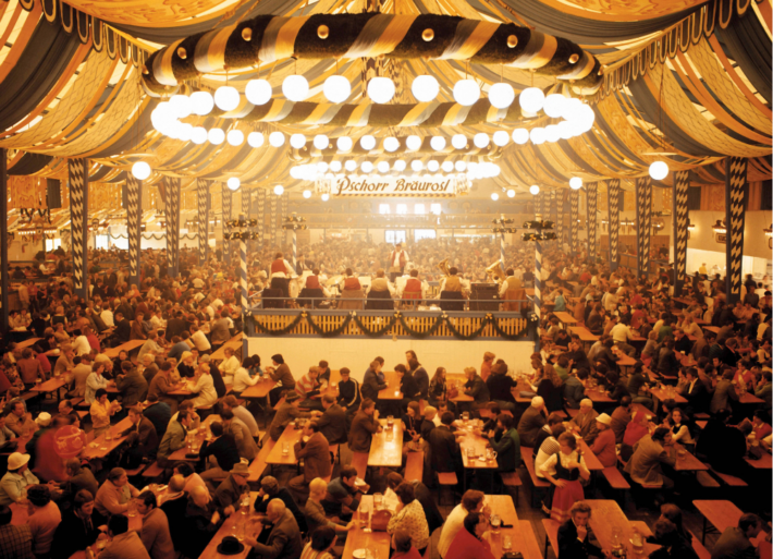 Festzelt vom Oktoberfest von innen. Menschenmengen feiern an tischen