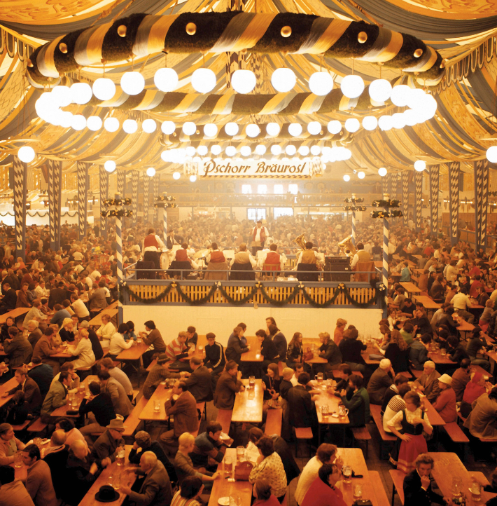 Festzelt vom Oktoberfest von innen. Menschenmengen feiern an tischen